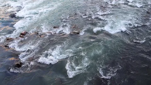 The water flows in the river at speed and hits the rocks Stock Footage 308164197