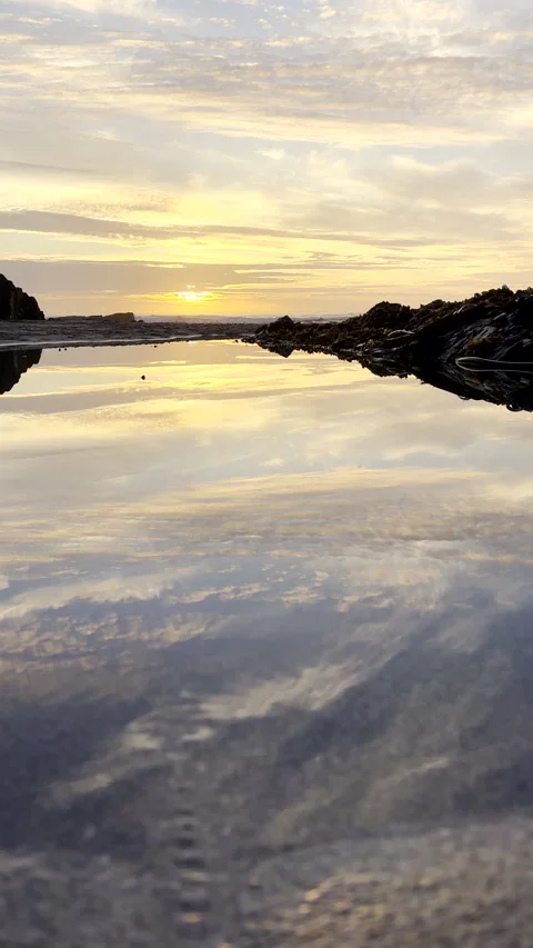 Water flows into rock pool as vibrant sun sets over ocean with perfect sky Vídeos de archivo 331390150