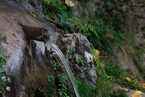 Water flows from a rusty iron pipe in the Alcoy waterfall Фото