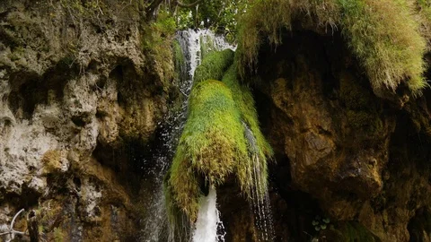 Water flows in sharp rocks covered with green grass. Bottom view on overhanging Stock Footage 126242094