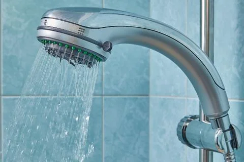 Water flows from shower head, fixed in holder inside bathroom. Stock Photos