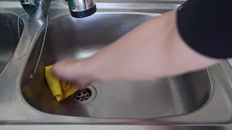 Water flows into the sink while a person uses a sponge to clean the surface Stock Footage 342930625