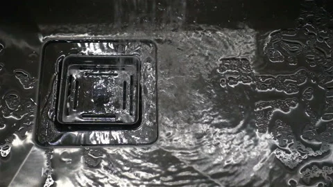 Water flows in a slow motion into a square sink of a metal sink Stock Footage 133036738