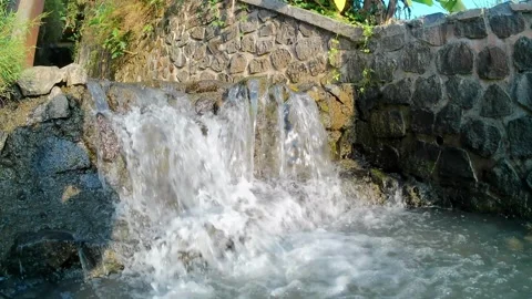The water flows in a small canal towards a river with many rocks Stock Footage 243408199