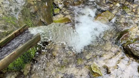 Water that flows from the spring in the mountains and descends through a gutter Stock Footage 251512632