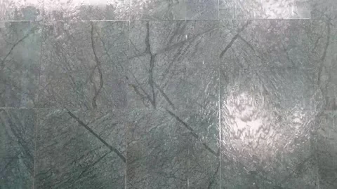 Water flows from a stone along the wall of a building on a sunny day. Stock Footage 168079072