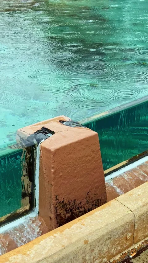 Water flows from stone structure into clear pool at tropical location during Stock Footage 332972255
