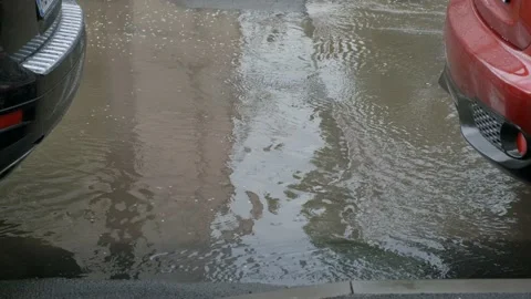 Water flows in a strong stream after rain between cars. Stock Footage 130545729