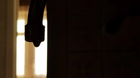 Water flows from a tap against the backdrop of the setting sun, slow motion Stock Footage 315510202