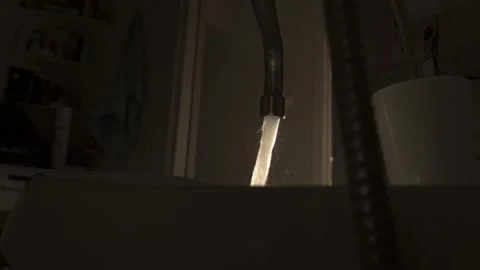 Water flows from a tap against the backdrop of the setting sun, slow motion Stock Footage 317806573