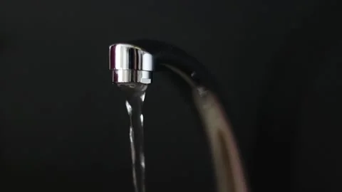 Water flows from the tap on a black background. Stock Footage 163148774