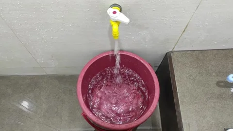 Water flows from the tap into the red bucket Stock Footage 273475298