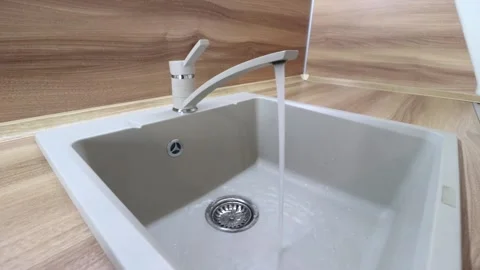 Water flows from the tap into the sink . Kitchen sink. The sink is ceramic. Stock Footage 143559811