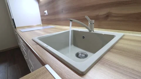 Water flows from the tap into the sink . Kitchen sink. The sink is ceramic. Stock Footage 144721598