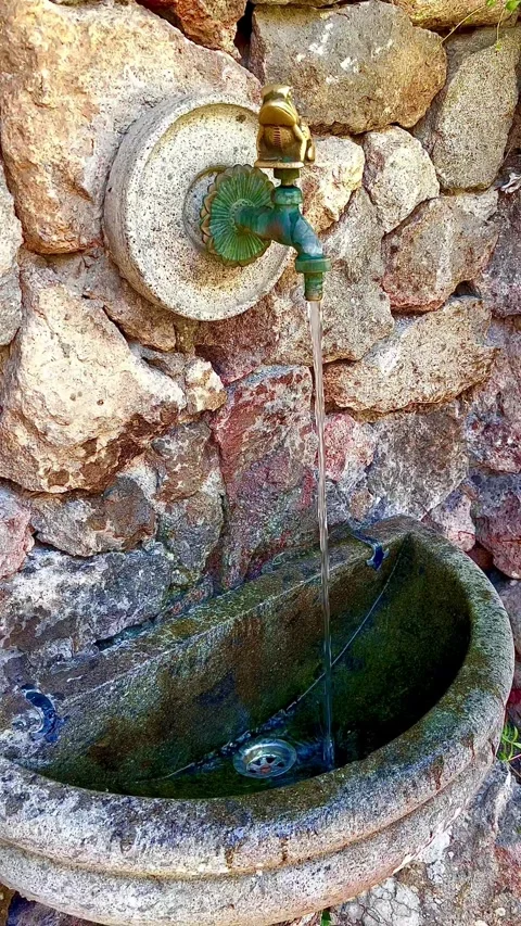 Water flows from a tap on a stone wall. Stock Footage 310661391