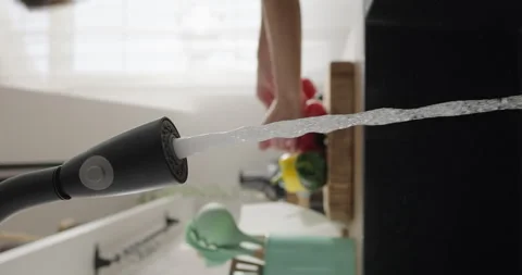 Water flows from the tap while woman cooks in the kitchen. Water pours from Stock Footage 264758649