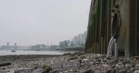 Water Flows into the Thames from a Drainage Pipe, London in the background Stock Footage 291088402