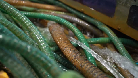 Water flows from thick rubber pipes cooling overheated machinery Stock Footage 304383998