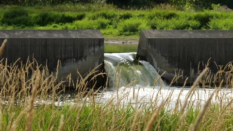Water flows through the floodgate in a concrete dam on a river. Stock Footage 146715766