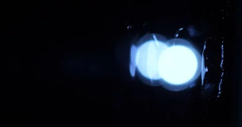 Water flows through the glass in the dark against a background of a headlight Stock Footage 84211075