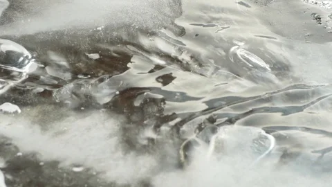 Water flows through ice, air bubbles under the ice, close-up Stock Footage 124495031