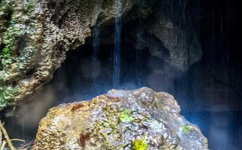 Water flows through rocks in the cave. A small waterfall at the entrance to t Stock Photos