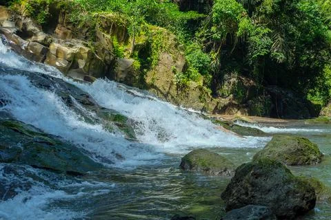 The water flows through the rocks in the middle of the forest. Small waterfal Stock Photos