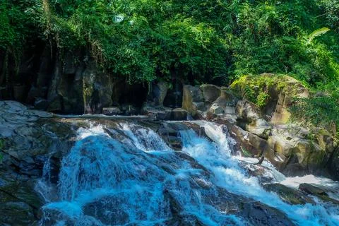 The water flows through the rocks in the middle of the forest. Small waterfal Stock Photos
