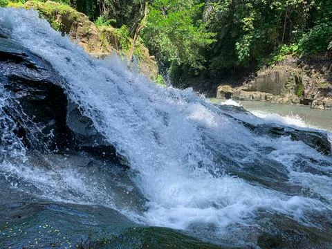 The water flows through the rocks in the middle of the forest. Small waterfal Stock Photos