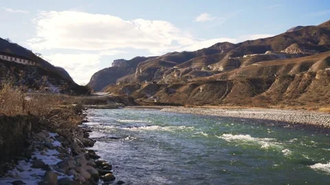 Water flows through valley surrounded by mountains, creating natural landscape Stock Footage 271479395