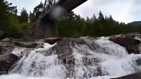 Water flows under a bridge in Norway with trees and rocks in the background.. Stock Footage 340215230