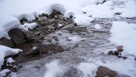 Water flows under the ice, a river, a stream in winter, water flows in the m Stock Footage 242864226