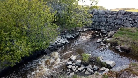 Water flows from under the old stone wall Stock-Footage 107760111