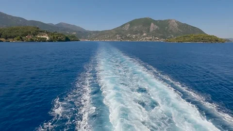 Water foam trace behind the ship with island in the background Stock Footage 317549384