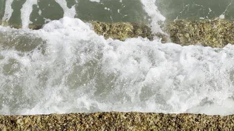 Water foaming over pebbled edge close up Stock Footage 336503774