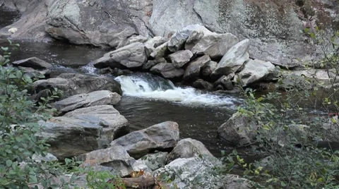 Water gently flowing in a stream over large rocks Video stock 8835791