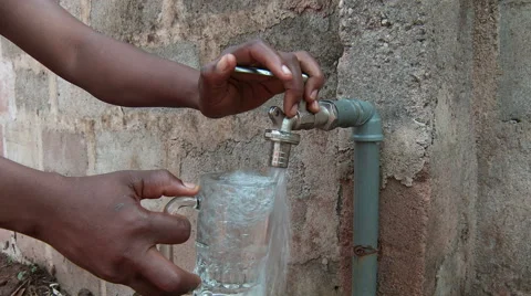 Water glass filled at outside faucet, Africa. Stock Footage
