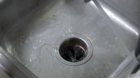 Water going down the drain of a dirty, metal kitchen sink 스톡 동영상 314244347
