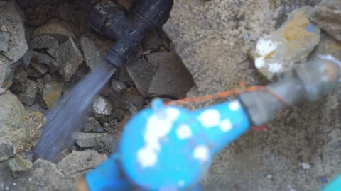 Water gushes from a ruptured underground pipe in a rocky excavation pit. Pr.. Stock Footage 331280491
