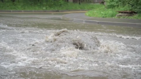 Water gushes from the storm drain. A stream of dirty water floods the roadway Stock Footage 132049365
