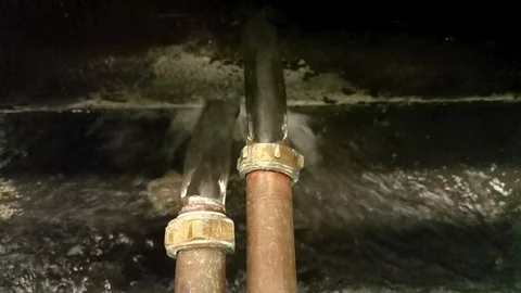Water gushing from two copper overflow pipes into a gully Stock Footage 79700115