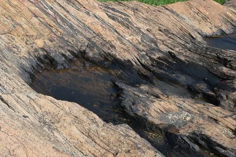 Water has collected on the rock's surface. Stock Photos