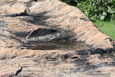 Water has collected on the rock's surface. Stock Photos