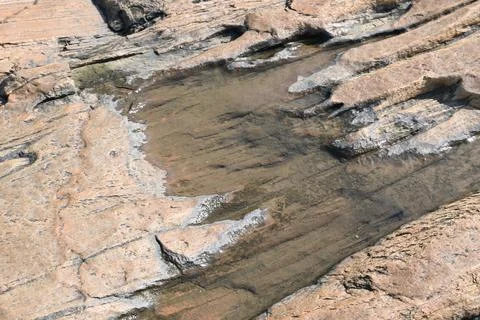 Water has collected on the rock's surface. Stock Photos