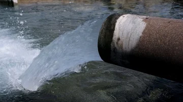Water heavily flows out of an irrigation pipe into a reservoir. Stock Footage