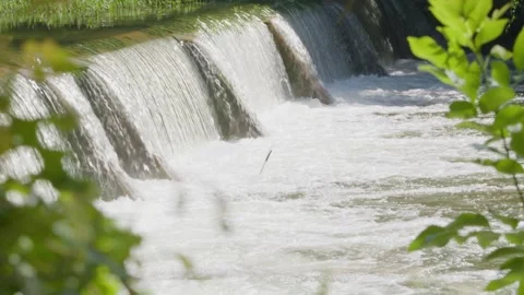 Water from heavy rainfall flows over small dam on Texas river Stock Footage 335597773