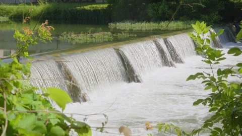 Water from heavy rainfall runs over small dam on Texas river Stock Footage 335598566