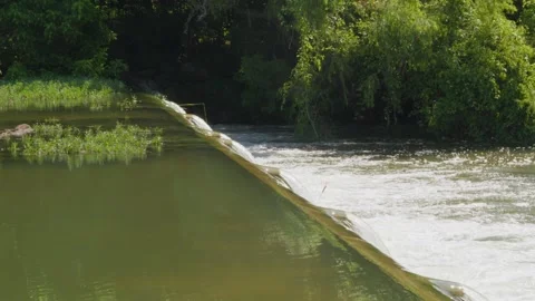 Water from heavy rainfall runs over small dam on Texas river Stock Footage 335598592