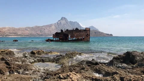 Water hitting the rocks with a shipwreck in the background. Stock Footage 155625858
