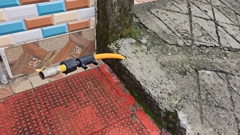 Water hose connector lying on red tiled pavement next to concrete curb Vídeo Stock 342586765